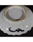 White porcelain plate with black bamboo and calligraphic brushwork, black base mark, close-up against dark background.