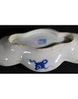 White ceramic cloud-form dish with wavy rim, blue floral and figural river scene, marked base, close-up.