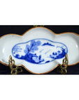 Blue and bronze antique cloud-form dish with figural river scene, displayed on a metal stand.