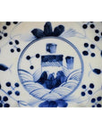 Blue and white porcelain plate with hand-painted abstract garden and floral design, close-up view.