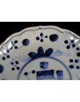 Close-up of a blue and white hand-painted Chinese porcelain plate with floral and geometric rim patterns.