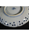 Close-up of the blue and white ceramic underside of a Chinese hand-painted porcelain plate with circles and rim dots.