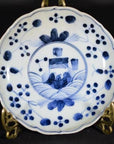 White porcelain plate with hand-painted floral and garden design, displayed on a decorative metal stand.