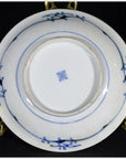 Close-up of underside of antique Chinese porcelain plate with oxen and lattice border, displayed on a metal stand.