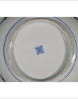 Close-up of white porcelain Chinese plate base with blue square center mark and blue rings around the foot.
