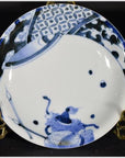 Blue and white porcelain plate with hand painted oxen and lattice border, displayed on a brass stand.