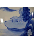 Blue and white porcelain plate with hand painted seated scholar by a river, antique Chinese style, close-up.