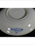 Close-up of the underside of a white porcelain plate with a small blue floral design near the base.