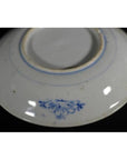 Close-up of the underside of a white porcelain plate with a small blue floral design near the base.