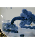 White porcelain plate with hand-painted blue clouded mountain landscape, close-up.