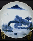 White porcelain plate with hand painted Clouded Mountain landscape design, displayed on a decorative stand.