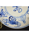 Blue and white porcelain plate with hand-painted crab and longevity motifs, antique Chinese close-up.