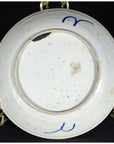 Close-up of blue and white porcelain underside with hand-painted marks, chips, and discoloration visible.