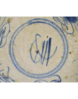 Blue and white porcelain plate with hand-painted butterfly and abstract floral design, close-up.