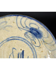 Close-up of a cream porcelain plate with blue floral designs and a butterfly, antique Chinese hand-painted style.