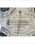 Close-up of an antique painted porcelain plate with abstract radial lines and a floral ring design.