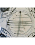 Close-up of an antique painted porcelain plate with abstract radial lines and a floral ring design.