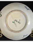 Close-up of the underside of an antique painted porcelain plate with abstract radial lines and a floral ring on black.
