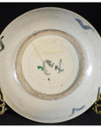 Close-up of the underside of an antique painted porcelain plate with abstract radial lines and a floral ring on black.