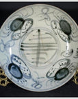 White porcelain plate with abstract radial lines and floral ring, displayed on a gold stand.