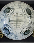 White porcelain plate with abstract radial lines and floral ring, displayed on a gold stand.