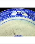 Close-up of blue and white ceramic plate with radial medallion design, blue loop border, and crackled glaze.