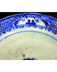 Close-up of blue and white ceramic plate with radial medallion design, blue loop border, and crackled glaze.
