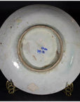 Blue ceramic plate with radial medallion pattern on a decorative metal stand.