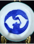 Metal circular dish with antique crane and turtle design, displayed on a metal stand, symbolic embrace motif.