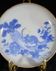 Antique painted ceramic dish with mouse duo and radish garden scene, displayed on a brass stand.