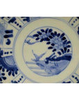 Blue and white porcelain plate with hand painted bird, floral, and geometric motifs, antique Chinese design, close-up.
