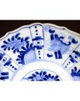 Blue and white porcelain plate with intricate hand painted floral and geometric patterns, antique style, close-up.