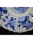 Blue and white porcelain plate with hand painted floral and geometric patterns, antique Chinese, scalloped edge, close-up.