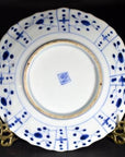 Blue and white hand painted porcelain plate with geometric dot design, blue stamp underneath, displayed on gold stand.