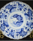 White porcelain plate with hand painted floral and bird designs, displayed on a brass stand.