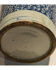 Close-up of blue and white ceramic vase base, hand painted, with unglazed rim and slight staining.