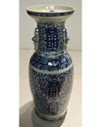 Close-up of blue and white ceramic Chinese vase with floral patterns, decorative handles, and weathered finish.