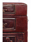 Close-up of dark red lacquer antique Chinese jewelry box with worn edges and carved drawers.