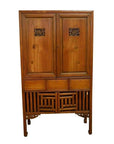 Brown wooden Chinese kitchen cabinet with hand-carved details, two doors, and three drawers, front view.