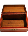 Red lacquered wooden box with metal-hinged lid, rectangular and open, shown against a plain background.