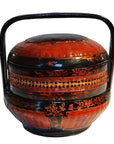 Red and black lacquered Chinese lunch box with handle, floral designs, and intricate patterns, close-up view.