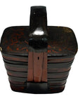 Red lacquered Chinese tiered food basket with handle, floral designs, and striped banding, close-up view.