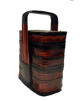 Red and black lacquered Chinese tiered food basket with handle, antique finish, isolated on white background.