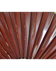 Close-up of red pleated and gold-trimmed antique Chinese flags or fan, set against a white background.
