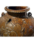 Close-up of brown glazed ceramic Martaban water jar with embossed patterns and ornate rim handles.