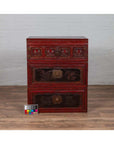 Red and black lacquered antique Chinese wooden chest with carved figures, three sections, on a wooden floor.
