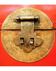 Close-up of ornate circular brass latch with floral engravings on red lacquer antique Chinese blanket chest.