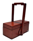 Close-up of antique Chinese red lacquer wood box with tall handle and two compartments, decorative display piece.