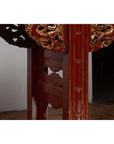 Close-up of red lacquered wood console table with carved apron and intricate decorative patterns.