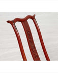 Close-up of a red lacquered wooden folding chair with carved back, footrest, and fabric upholstery.